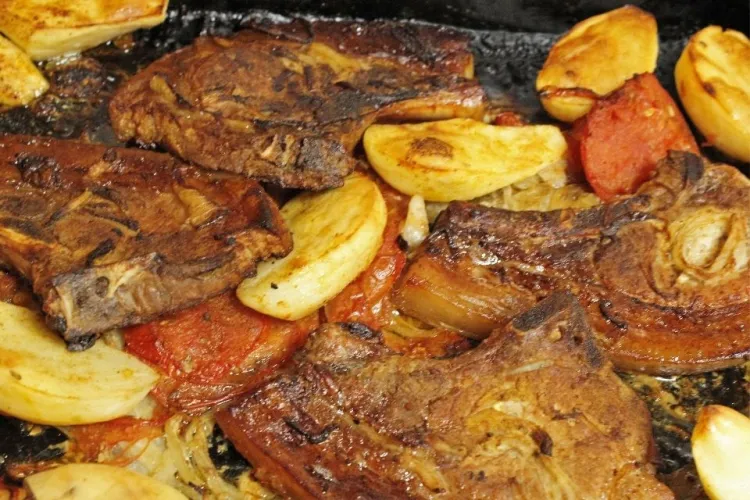 Chuletas de cerdo asadas al horno con patatas, tomate y cebolla.