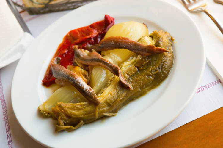 Un palto con escalivada adornada con filetes de anchoa.