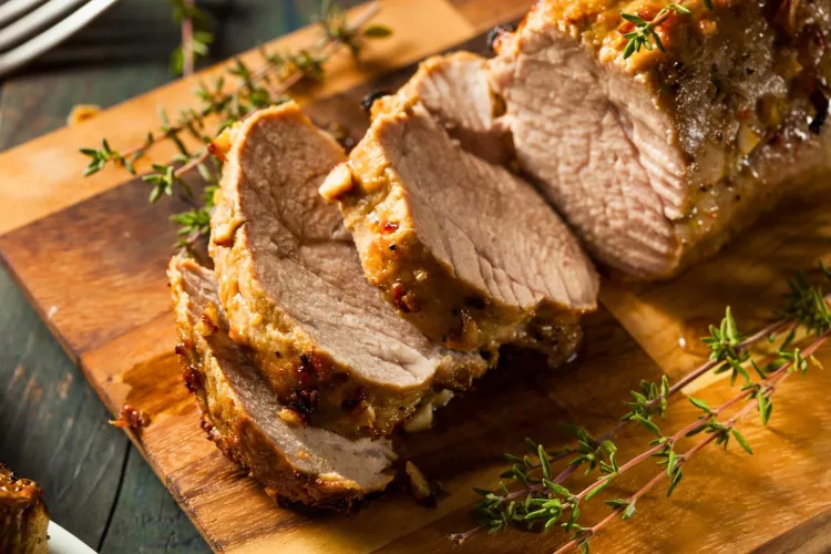 Solomillo de cerdo al horno cortado en medallones y acompañado de ramitas de tomillo.