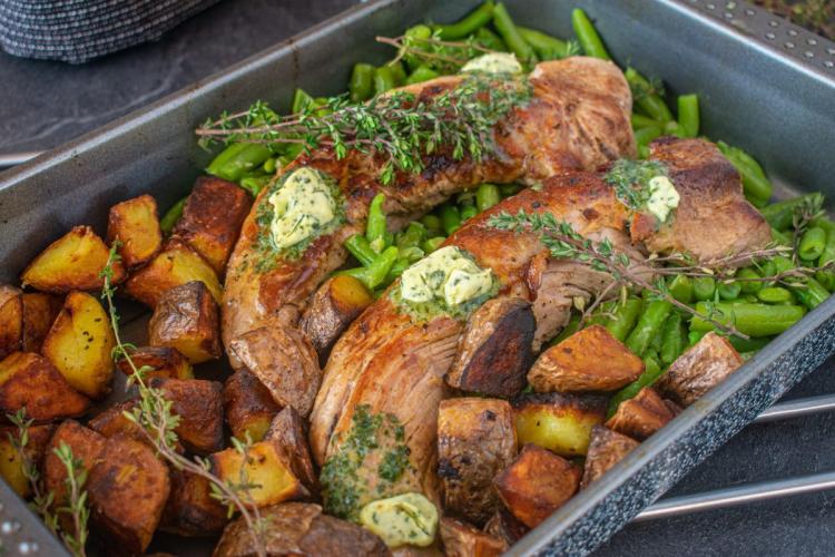 Una bandeja de horno con solomillo de cerdo al horno con patatas y judías verdes.