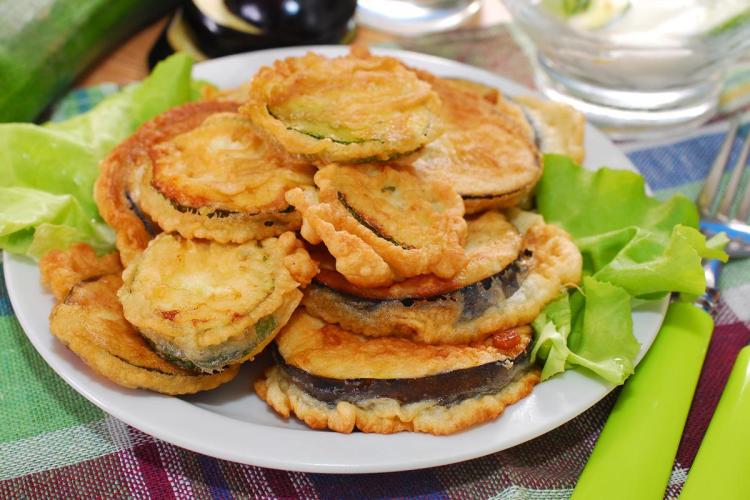 Un plato de berenjena y calabacín rebozados, servidos con lechuga.