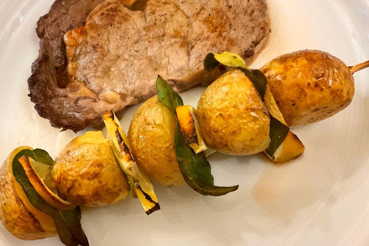 Una brocheta de patata con lima como acompañamiento de un filete a la plancha.