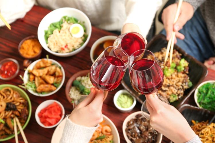 Comida china servida con vino tinto.
