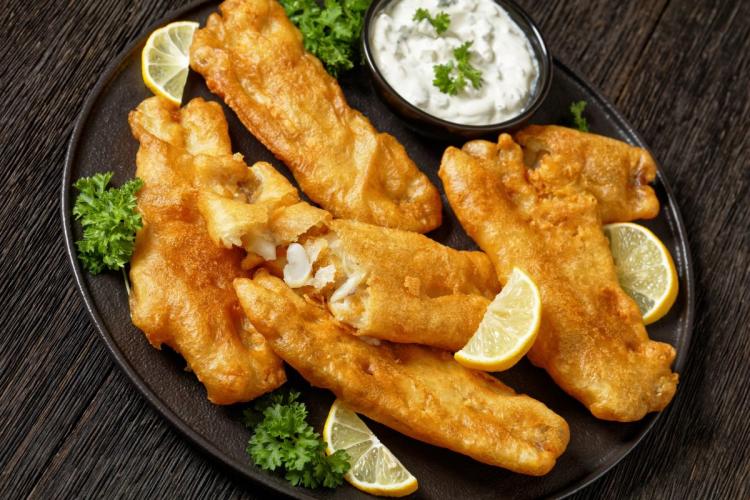 Un plato de pescado rebozado con masa de cerveza y frito, acompañado de salsa tártara.