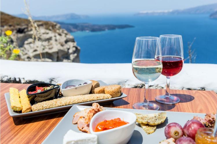 Comida y vino griegos en una terraza con vistas a un mar Mediterráneo de color azul brillante.
