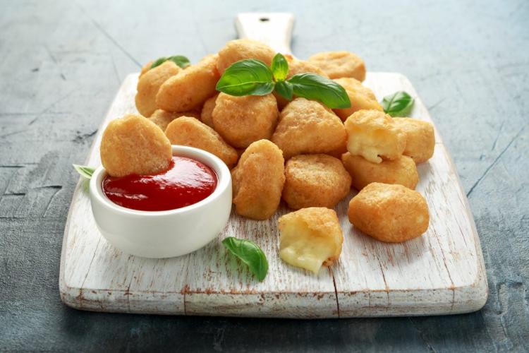 Bolitas de mozzarella rebozadas y fritas servidas con kétchup.