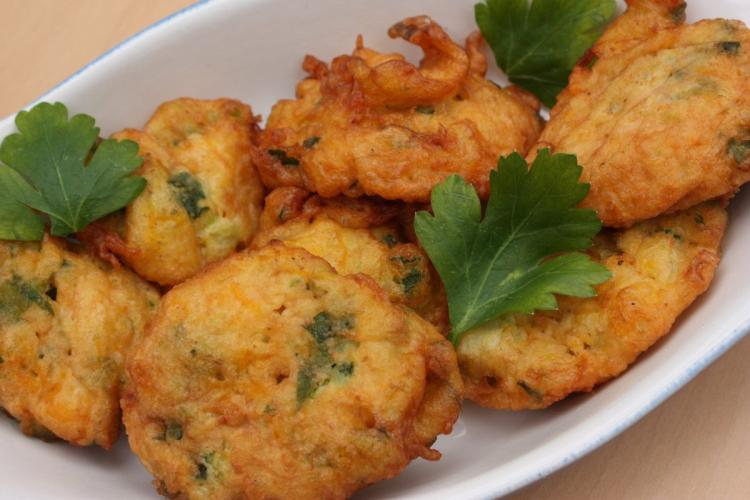 Buñuelos de calabacín bien dorados, decorados con perejil
