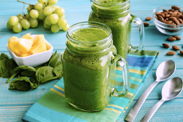 Dos tarros con batido de piña y espinacas tiernas.