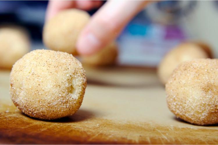 Pasando las bolas de masa por azúcar aromatizada con canela al hacer snickerdoodles.