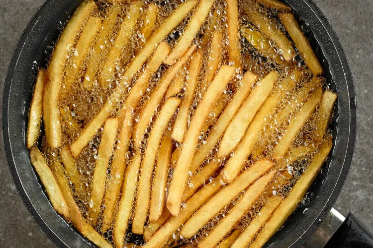 Patatas friéndose en una sartén con el aceite burbujeante.