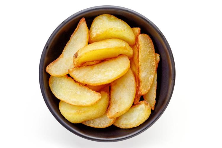Un cuenco con patatas fritas en forma de cuña gruesa.