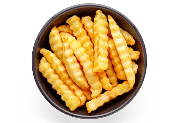 Un cuenco con patatas fritas cortadas en forma de varitas onduladas.
