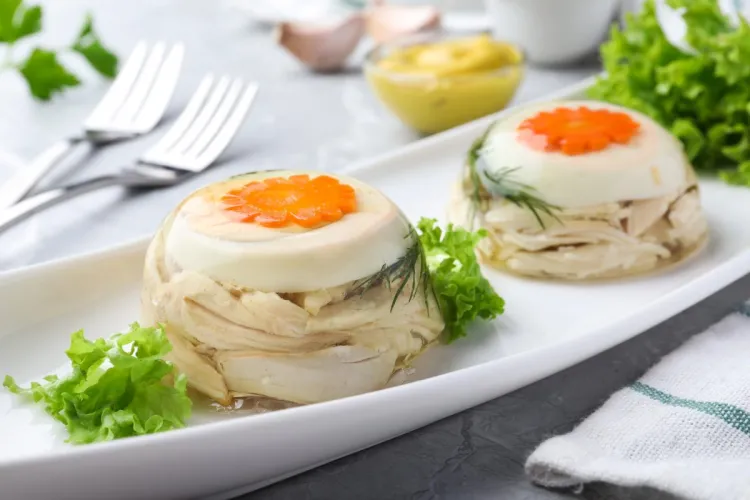 Dos áspic de ave de tamaño individual en una fuente blanca, adornados con hojas de ensalada.