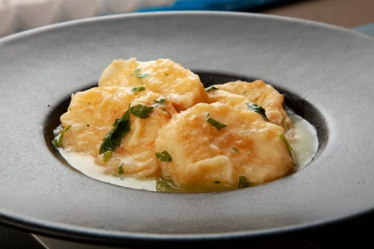 Un plato hondo de color gris con una porción de patatas a la importancia.
