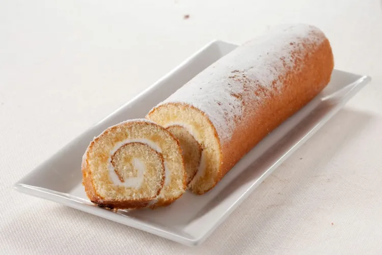 Brazo de gitano sencillo, relleno de mermelada y espolvoreado con azúcar glas sobre la superficie.