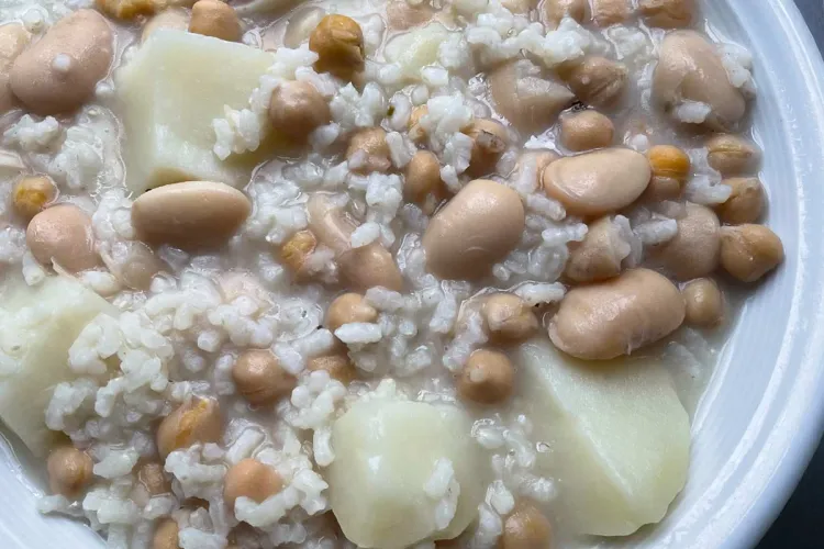Detalle de un plato de potaje blanco, con alubias blancas, garbanzos, patatas y arroz.