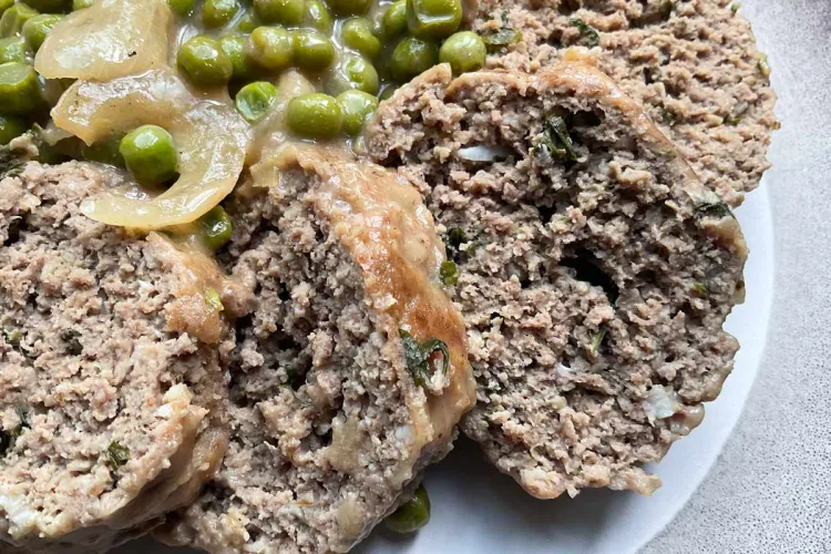 Detalle de rollitos de carne picada en salsa, cortados en rodajas gruesas.