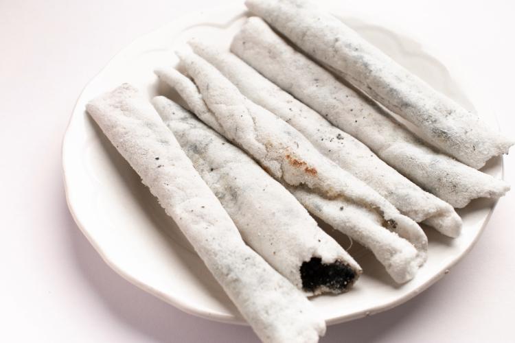 Un plato de loza blanca con rollitos de sésamo conocidos como til pita.