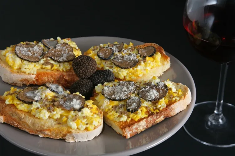 Un plato de tostadas con huevos revueltos con trufa negra.