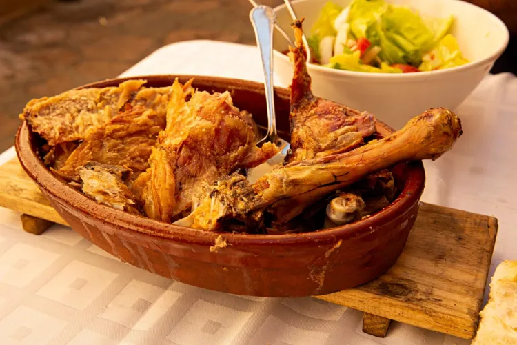 Una pierna de cordero asada al estilo tradicional, acompañada de una ensalada de lechuga.