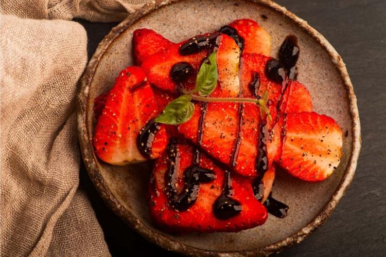 Fresas con pimienta y vinagre balsámico en un cuenco de cerámica artesanal.