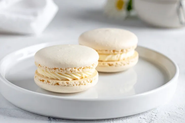 Dos macarons rellenos con crema de coco sobre un plato.
