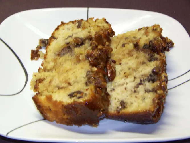 Dos rebanadas de pan de manzana glaseado servidas en un plato blanco.