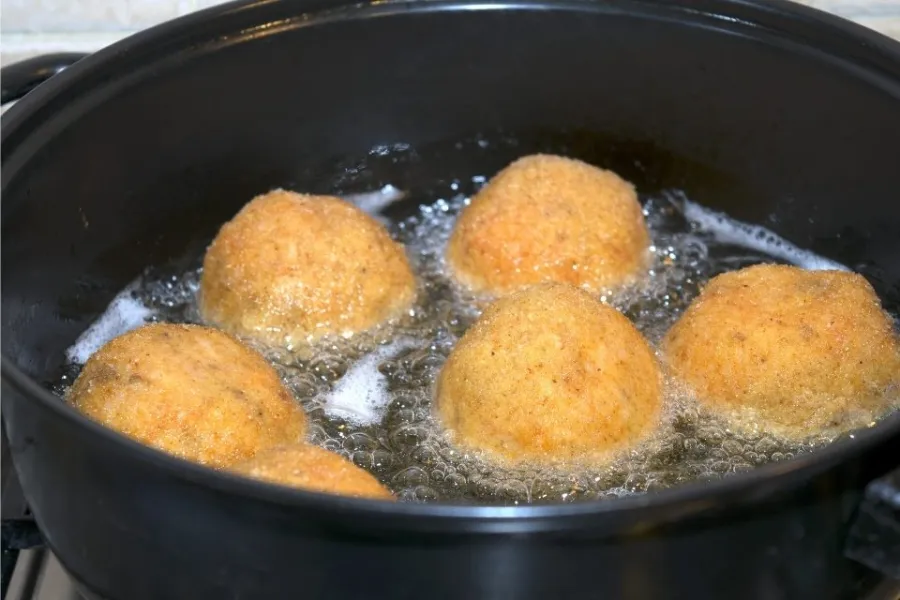 Croquetas de arroz, o arancini, friéndose.