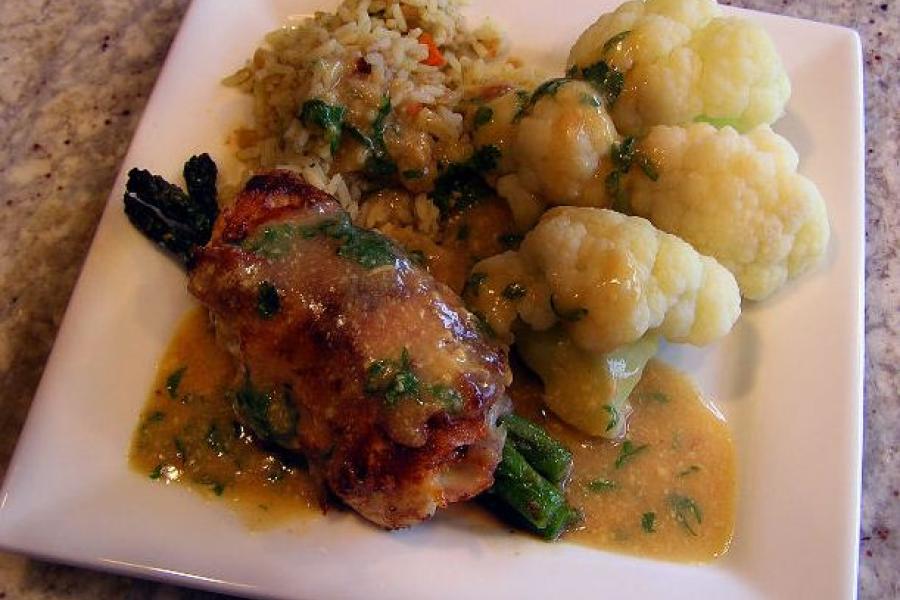 Un plato con carne, espárragos, coliflor y arroz.