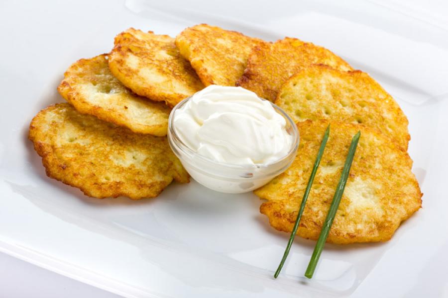 Tortitas de patata en un plato con nata condimentada y cebollino.