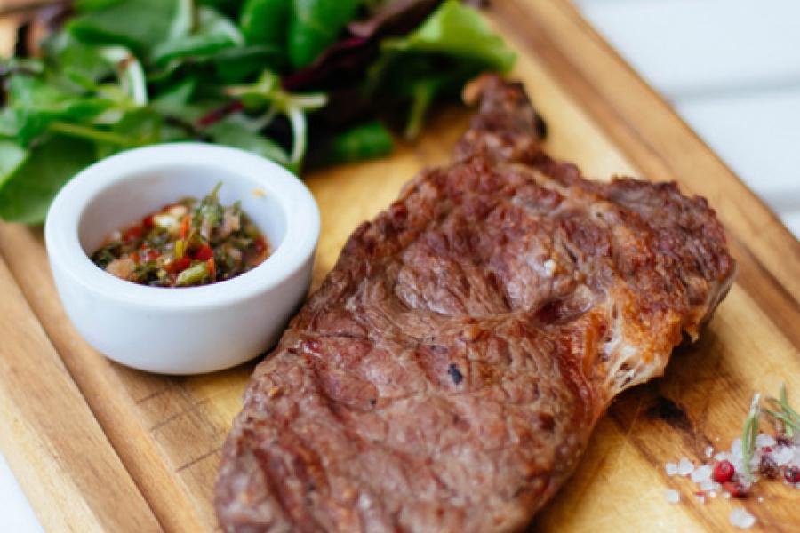Filete a la plancha sobre tabla de madera con salsa y rúcula.