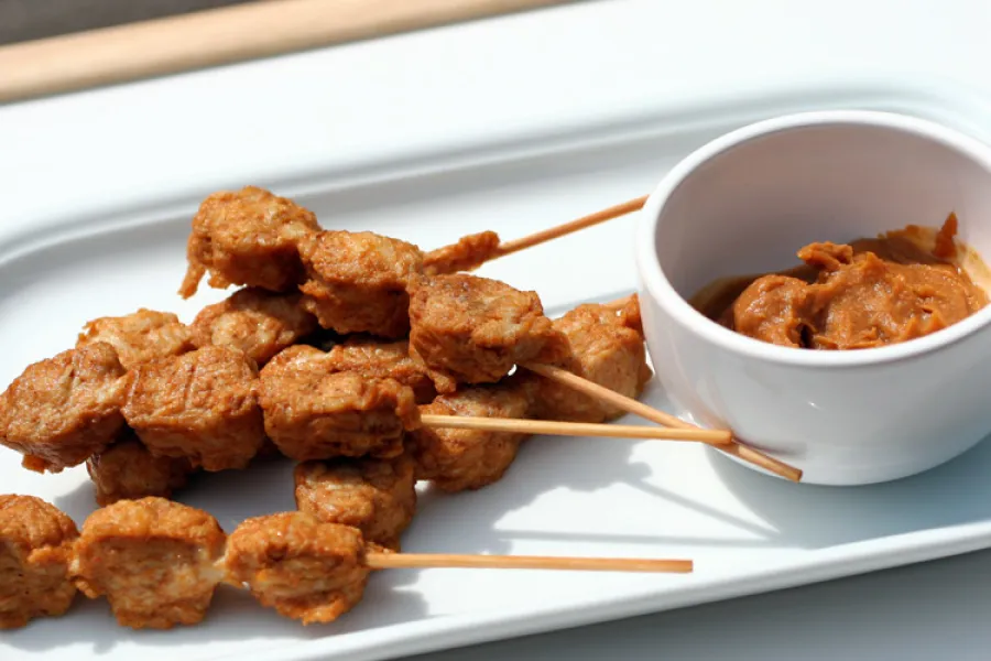 Satay de pollo con salsa de cacahuete para mojar.