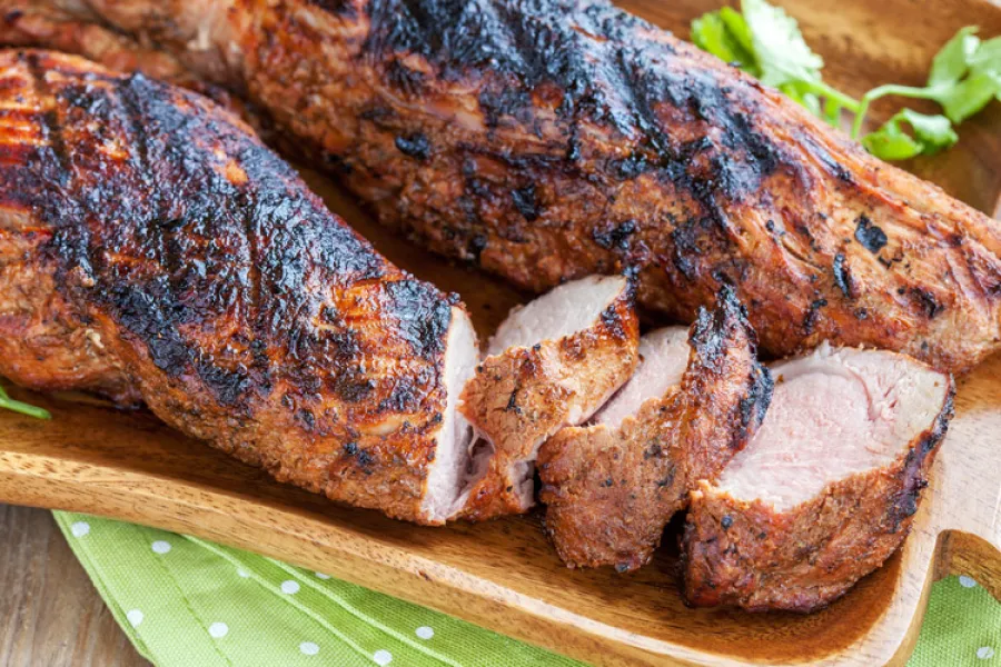 Dos trozos de solomillo de cerdo asado a la parrilla, se ha cortado algunos medallones de uno de ellos.