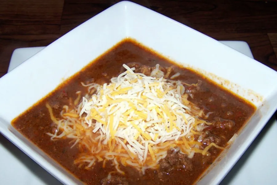 Chile con carne y mole en su plato con queso rallado por encima.