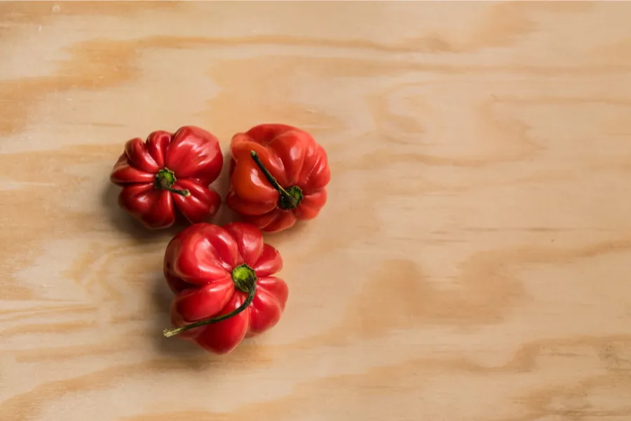 Tres chiles habaneros sobre tabla de madera.