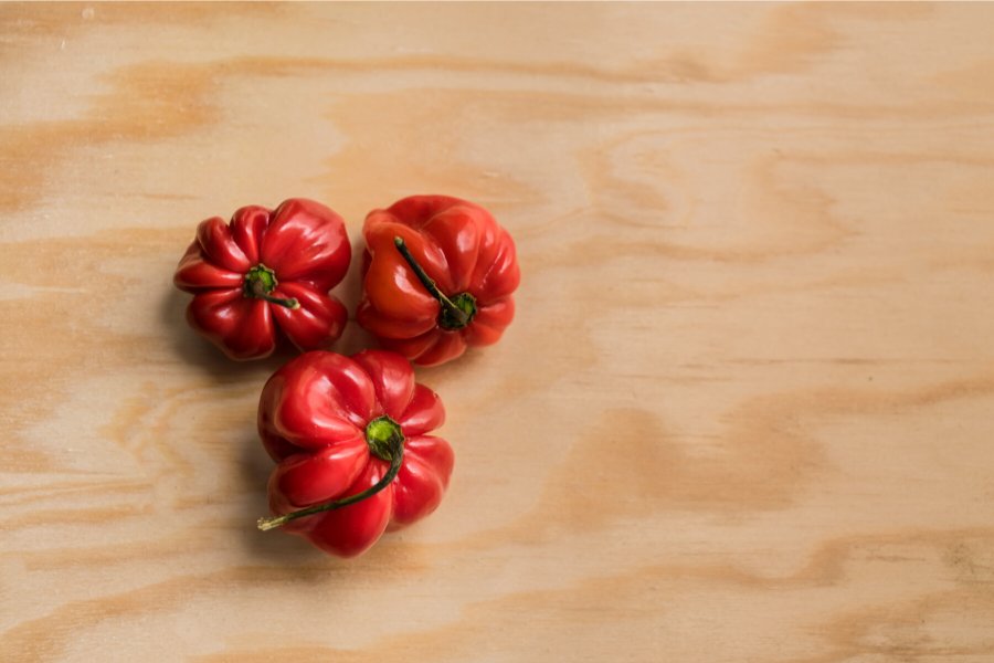 Tres chiles habaneros sobre tabla de madera.