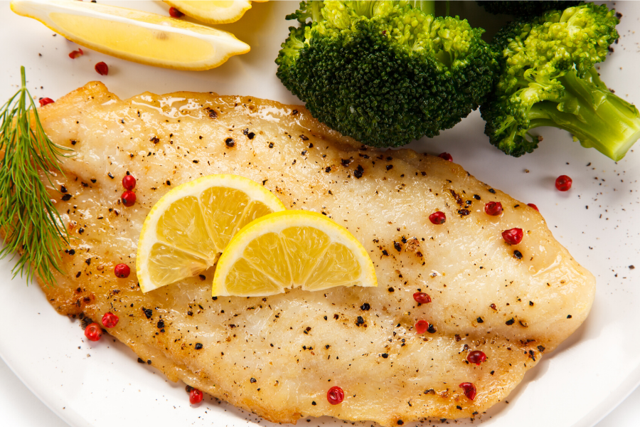 Filete de pescado a la plancha con salsa y verduras.