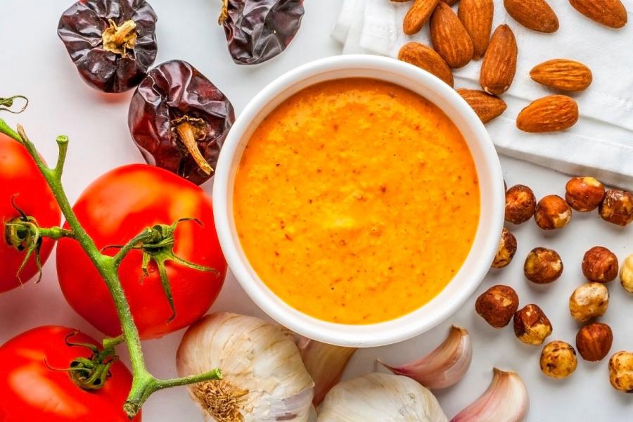 Un cuenco con salsa romesco para pescado rodeado de algunos de los ingredientes.