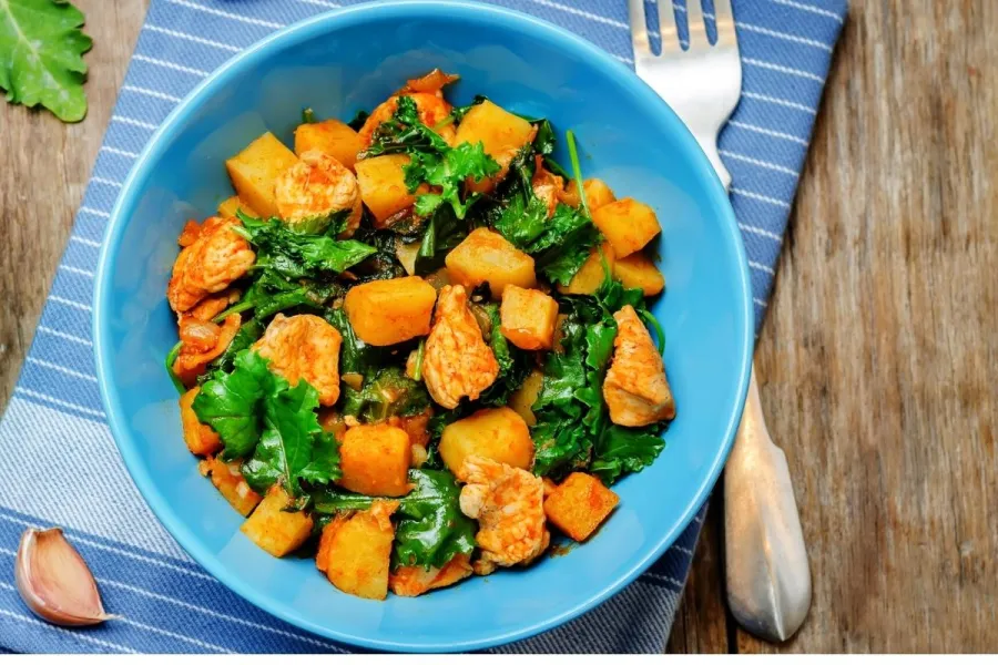 Guiso de pollo con batata y hojas verdes.