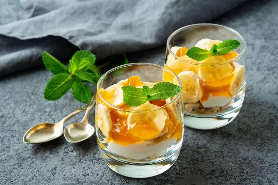 Copas de plátano y yogur decoradas con hojas de menta.