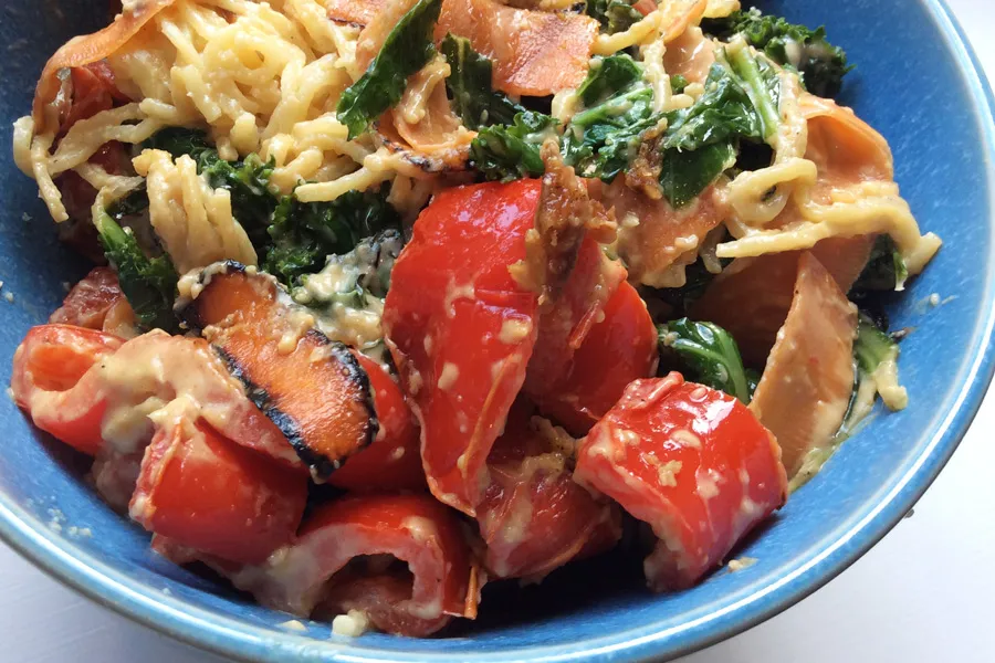 Cuenco con fideos chinos con verduras salteadas y salsa de cacahuete.