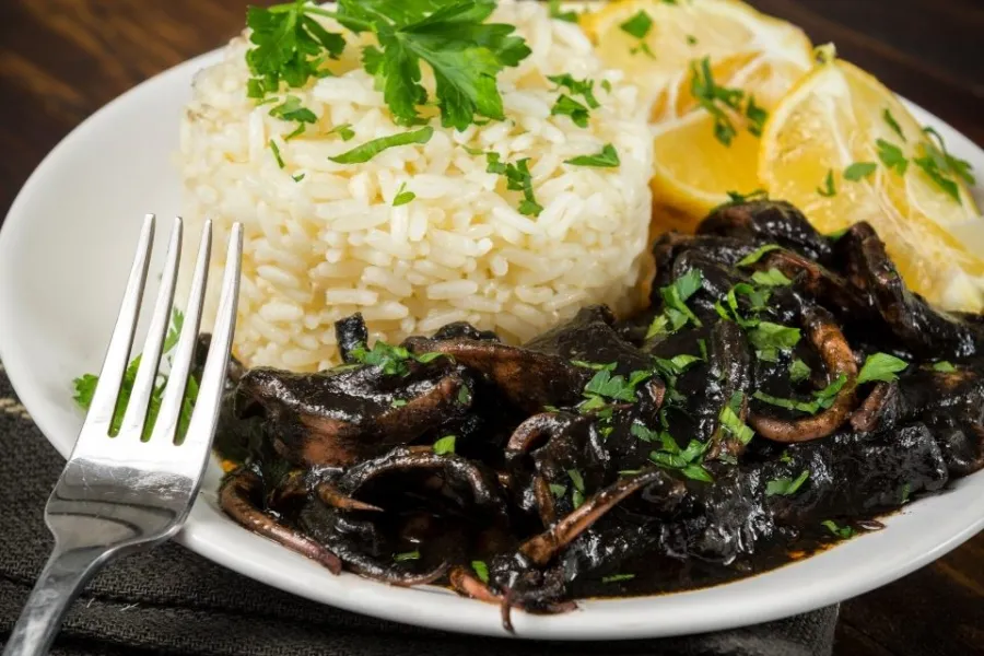 Un plato de calamares en su tinta con arroz blanco.