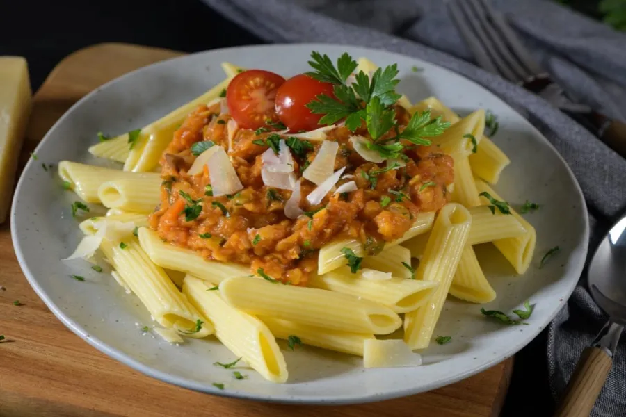 Un plato de pasta con salsa de lentejas.