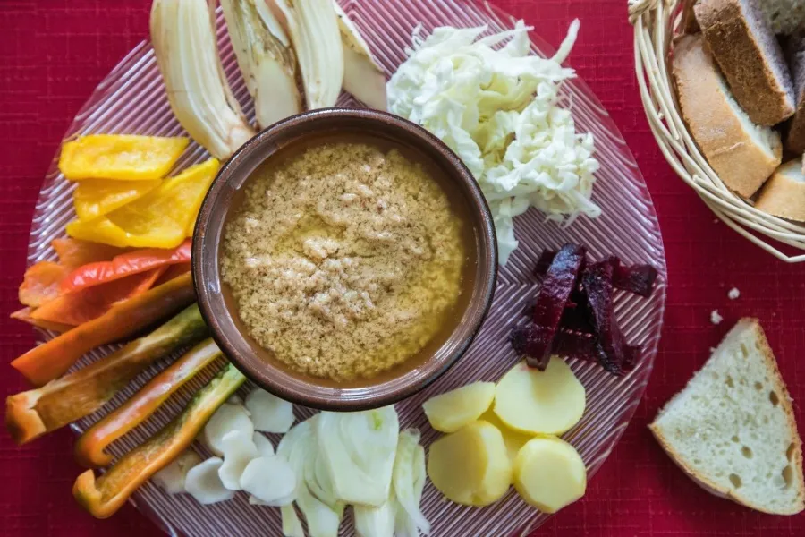 Un cuenco con bagna càuda rodeado de hortalizas troceadas.