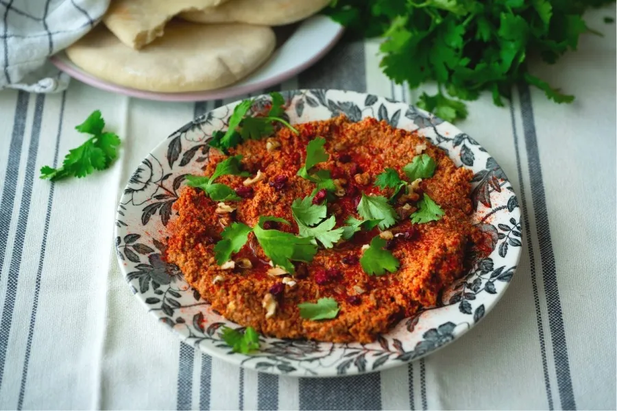 Un cuenco con muhammara decorada con perejil.