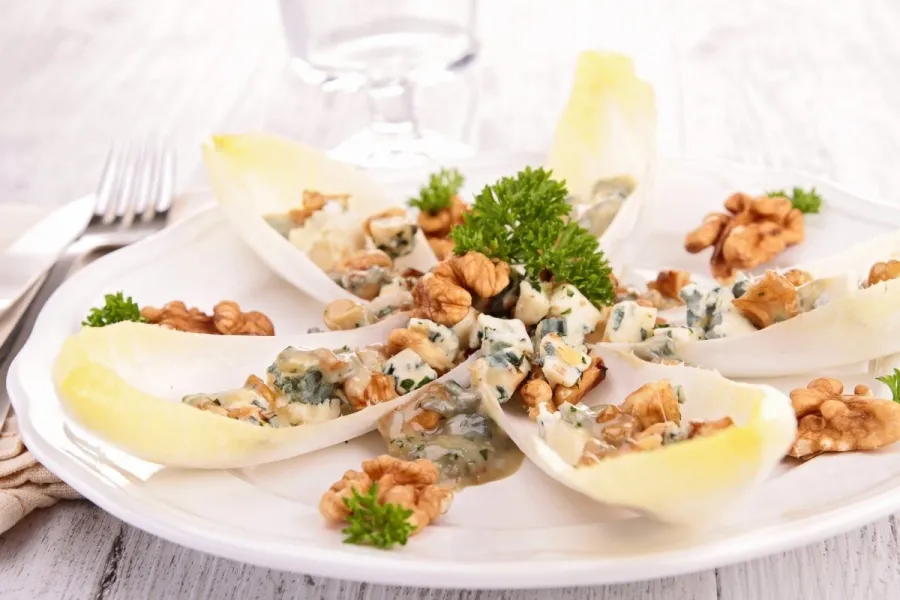 Un plato con ensalada de endibias y nueces con vinagreta al roquefort.