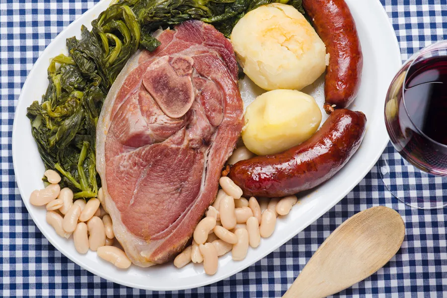 Un plato con el lacón cocido, grelos, patatas, chorizo y alubias blancas.