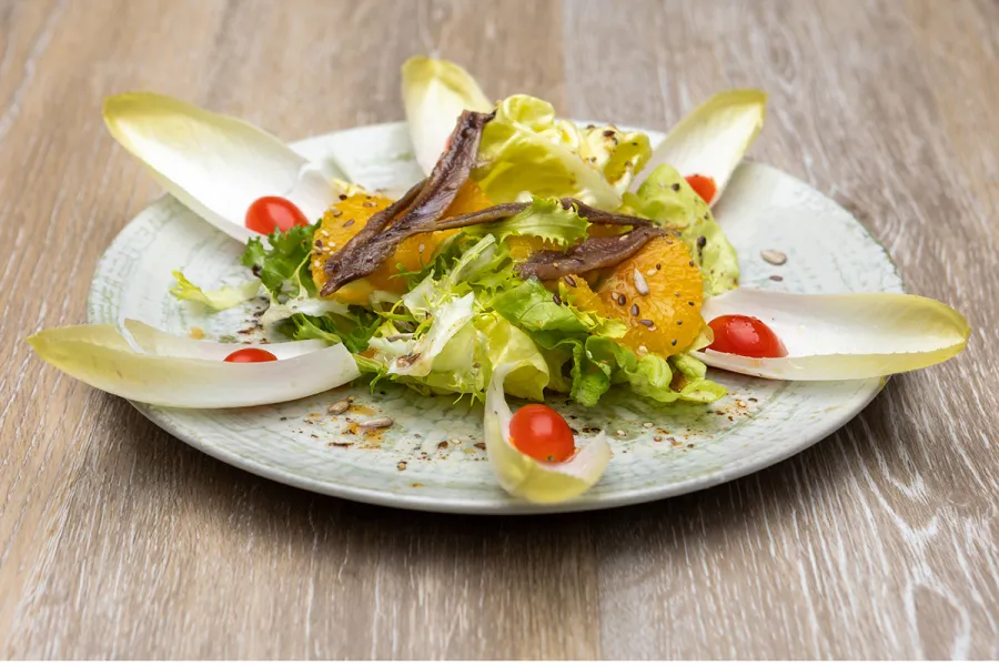 Ensalada de endibias con anchoas, tomate, naranja y lechuga.