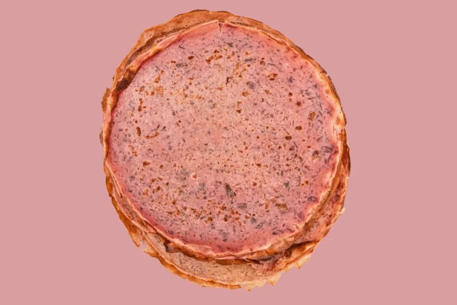 Tortitas rosadas estilo crêpe francés con trocitos de fruta y chocolate rallado.