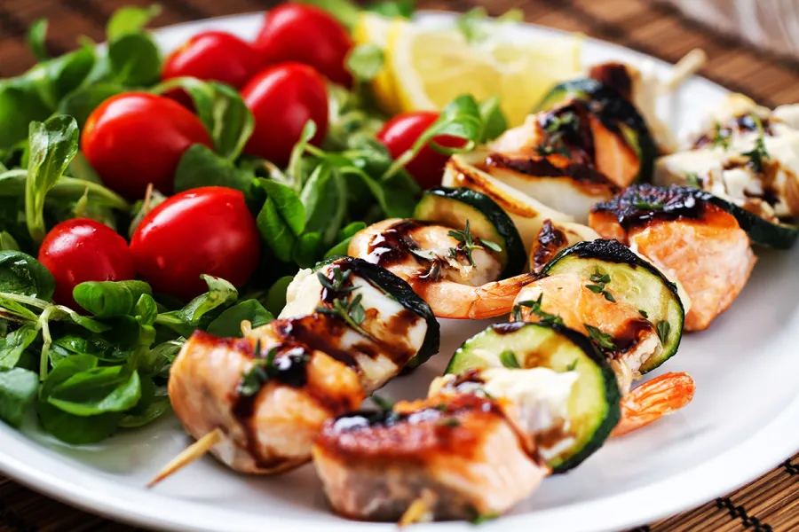 Brochetas de rape, salmón y langostinos acompañadas de ensalada.
